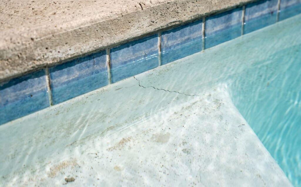 a weathered pool surface showing subtle plaster wear and a fine hairline crack